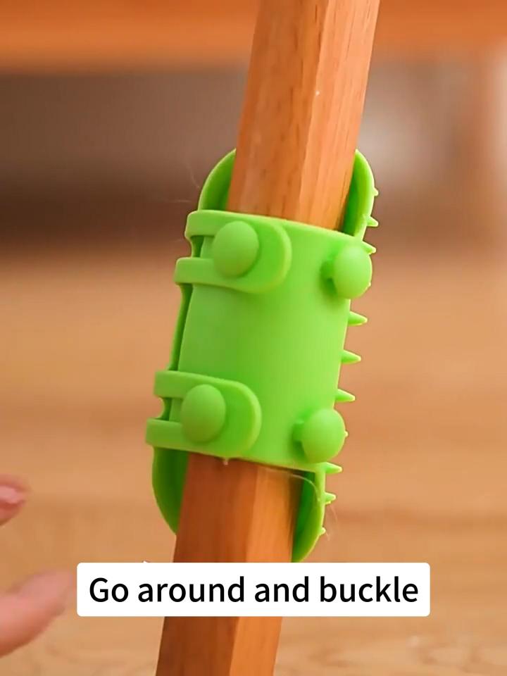 Green cat self-groomer wrapped and buckled around a chair leg